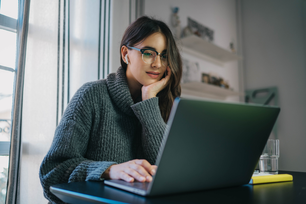 young hispanic woman looking at laptop for car insurance in texas