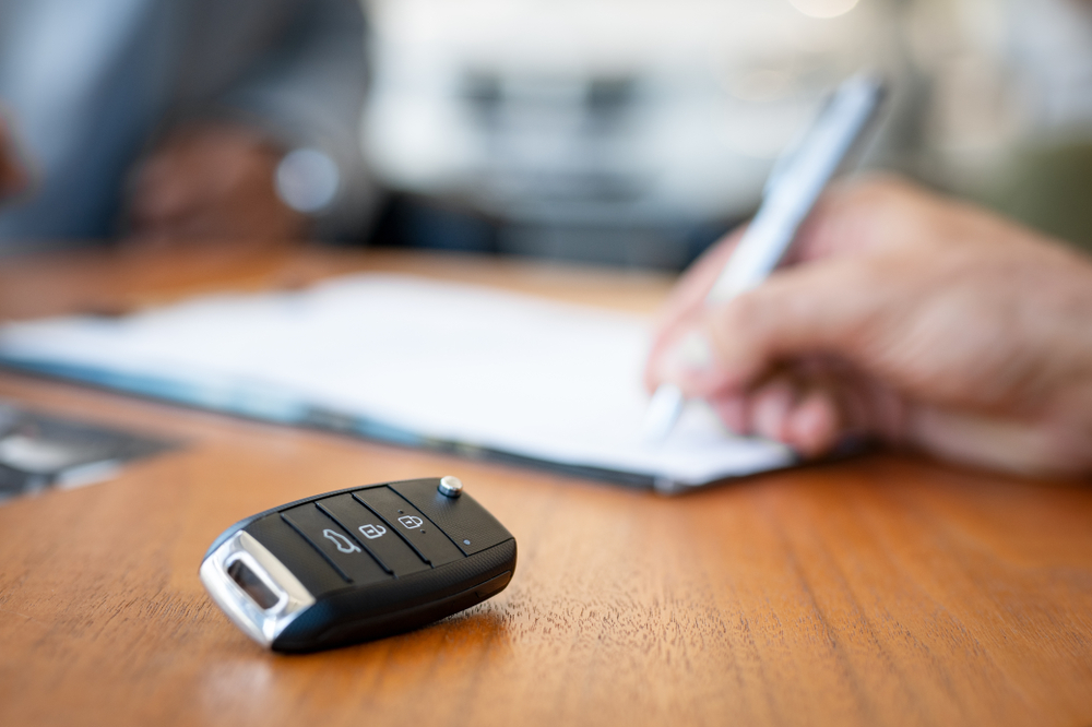 front view of car keys with someone signing in the background