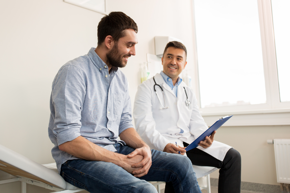 smiling doctor with clipboard and young patient talking about dependent health insurance