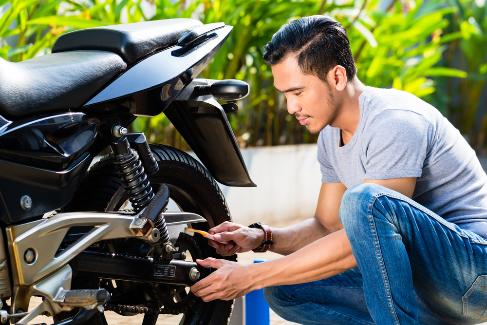 young asian man checking motorcycle